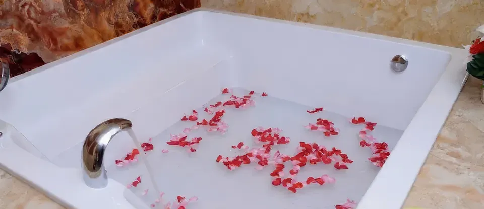 붉은 꽃잎이 띄워진 하얀색 사각 욕조