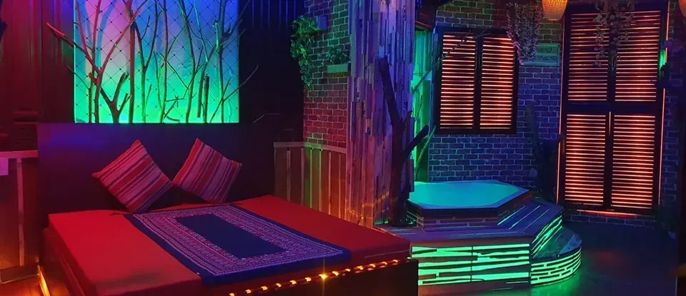 화려한 조명 아래 붉은 침대와 자쿠지가 있는 마사지룸