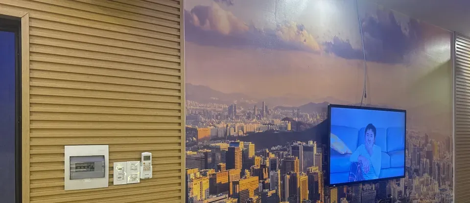 도시 야경 벽지와 모니터가 설치된 객실 벽면