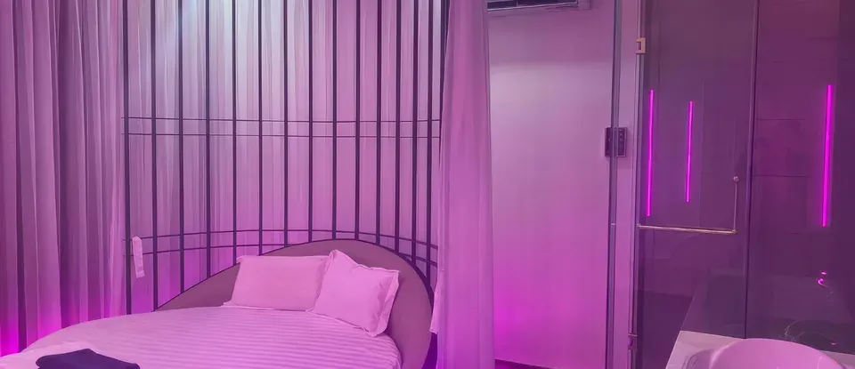 보라색 조명 아래 둥근 침대와 욕조