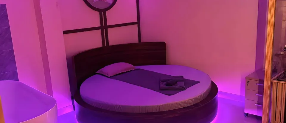 보라색 조명이 켜진 둥근 침대와 욕조